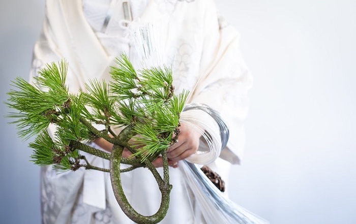 祭事で松を持ち白い着物を着た人